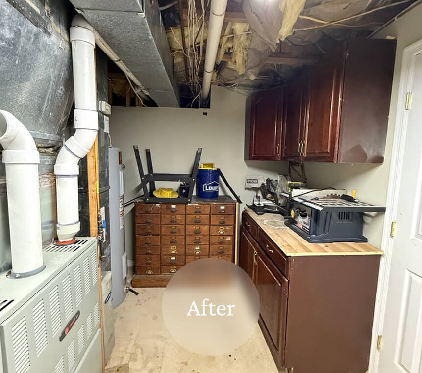 Liminal After Basement Storage 5 A small utility room with cabinets, a workbench, and tools, appearing clean and organized after renovation.