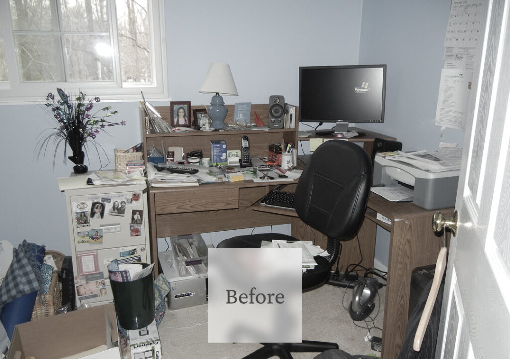 Liminal Before Bedroom Cleanup 3 A cluttered home office with a messy desk, scattered papers, and various electronic devices under a window.