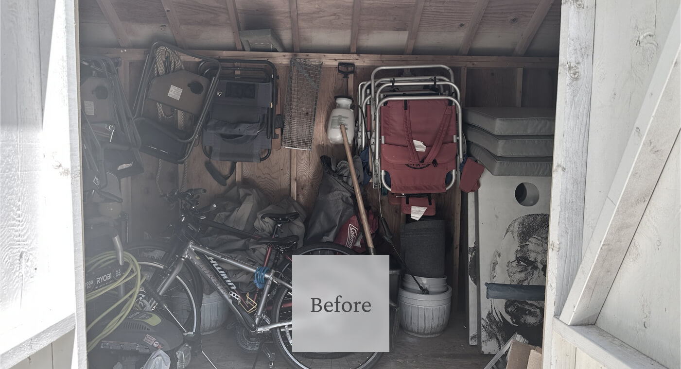 A cluttered storage shed with a bicycle, folded chairs, a red stroller, stacked mats, and various tools and supplies.